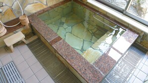 A stone-tiled hot tub with a granite countertop, a wooden bench, and a window view. - kinasse (Yamaga)