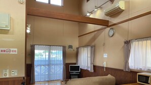 A room with wooden floors, a bed, a TV, a microwave, and a clock on the wall. - kinasse (Yamaga)