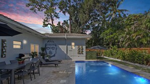 A modern outdoor pool area with a mural, a barbecue setup, and a dining area. - Tropical Oasis, Heated Pool, Near Las Olas Beach (Fort Lauderdale)