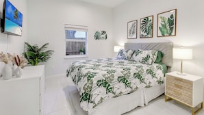 A bedroom with a bed, bedside table, and wall-mounted TV. - Tropical Oasis, Heated Pool, Near Las Olas Beach (Fort Lauderdale)