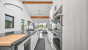 A modern kitchen with a wooden countertop, built-in appliances, and a view of the outdoors.