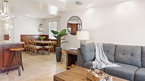 A modern living room with a grey sofa, wooden coffee table, and a dining area with a wooden table and chairs. - Gorgeous and Modern Duplex near the Beach! (Newport Beach)