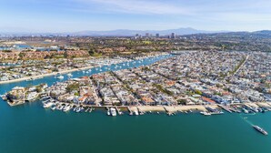 An aerial view of a coastal city with a marina filled with boats, residential areas, and distant mountains. - Gorgeous and Modern Duplex near the Beach! (Newport Beach)