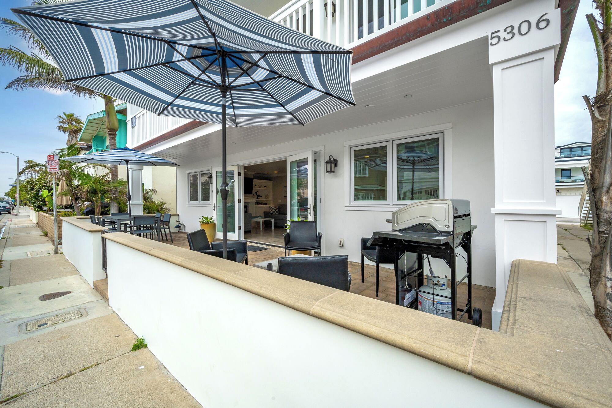 Ein Wohnobjekt mit überdachter Terrasse, Sitzgelegenheiten im Freien und einem Grill.