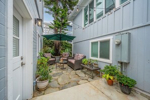 A patio with stone flooring, wicker furniture, and potted plants. - Laguna Perfection - Renovated Studio by the Ocean (Laguna Beach)