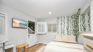 Ein Schlafzimmer mit Bett, einer Bank, einem Fernseher und einer Treppe.