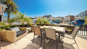 An outdoor patio with a table and chairs, surrounded by palm trees and a view of neighboring houses. - Beachside Getaway with Patio and Parking (Newport Beach)