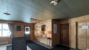 A check-in area with a reception desk, a sign indicating check-in procedures, and a wooden interior. - The Trail Inn - Newberry, MI - 13467 M-28 (Newberry)