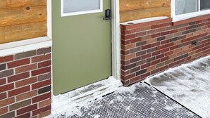 A wooden exterior with a green door, an office sign, and a window with a snow-covered ledge. - The Trail Inn - Newberry, MI - 13467 M-28 (Newberry)