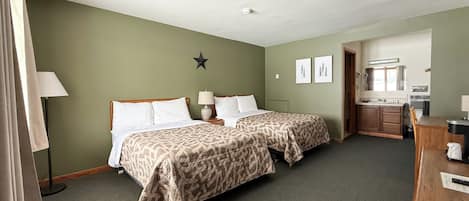 A hotel room with two beds, a star decoration on the wall, and a kitchenette in the corner.