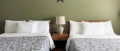 A hotel room with two beds, a star decoration on the wall, and a bedside table with a lamp.