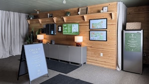 A reception area with a check-in desk, wooden wall panels, a map, and a refrigerator with an ice sign. - The Trail Inn - Newberry, MI - 13467 M-28 (Newberry)