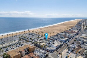 A coastal urban area with a beach, parking lots, and buildings.