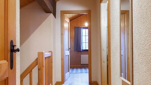 A narrow hallway with wooden railings and a door on the left.