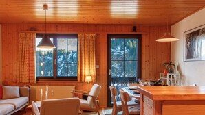 A cozy cabin interior with wooden walls, a dining area, and a sofa.