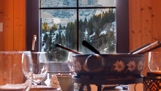 A dining table with a view of snow-capped mountains through a window.