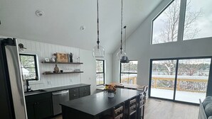 Une cuisine moderne dotée d’un îlot central, de grandes fenêtres et offrant une vue sur un paysage enneigé.