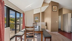 Un salon moderne avec un coin repas, de grandes fenêtres et une vue sur l’extérieur.