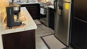 A modern kitchen with dark wood cabinets, stainless steel appliances, and a marble countertop.