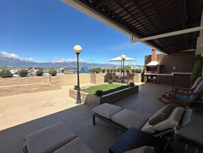 A rooftop patio with a grill, seating area, and a view of mountains. - Miller’s Townhouse (Ibarra)