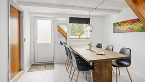Ein Essbereich mit Holztisch, schwarzen Stühlen, einer Pendelleuchte und einem Gemälde an der Wand.