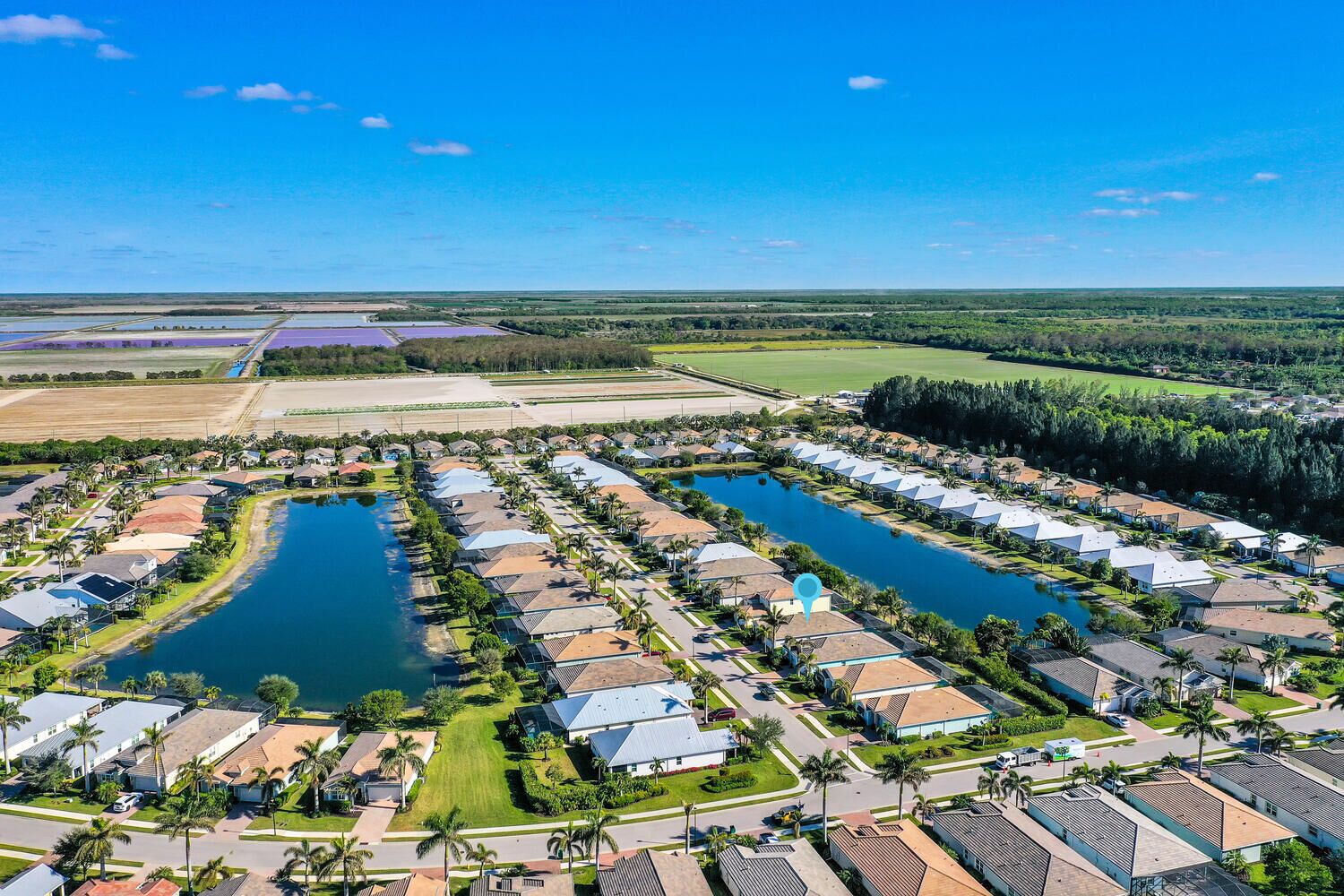 Luchtbeeld van een woongebied met meerdere huizen, een centraal waterpartij en omliggend groen.