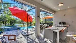 Um pátio moderno ao ar livre com piscina, área de refeições e churrasqueira.