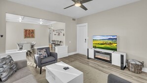 Una sala de estar moderna con un televisor de pantalla plana, chimenea y ventilador de techo.