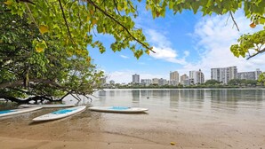 A beach with surfboards and a city skyline in the background.