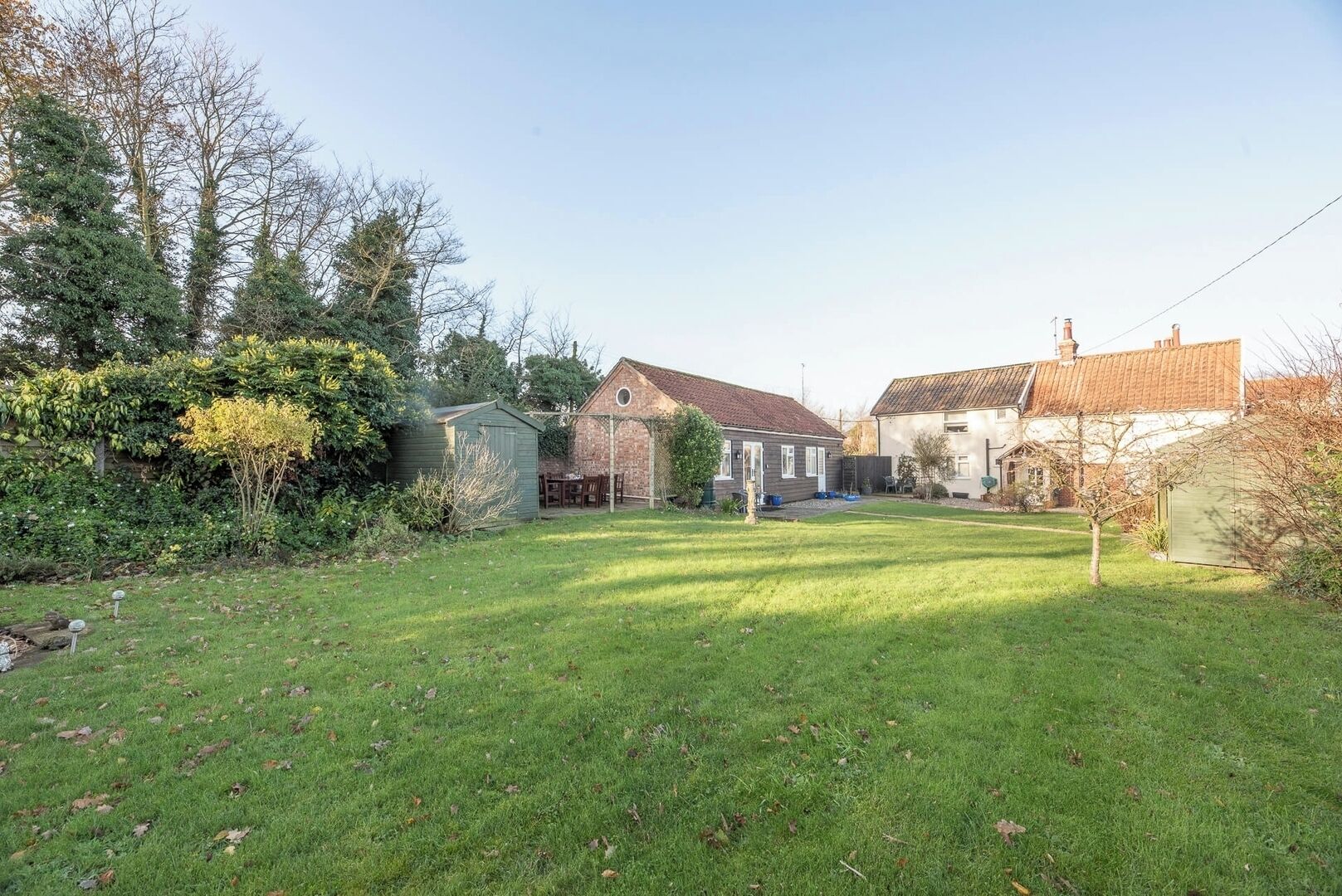 A residential property with a well-maintained lawn, a wooden deck, and a brick house with a tiled roof.