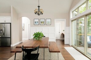 Una cocina amplia con una mesa de madera, un refrigerador y una lámpara colgante.