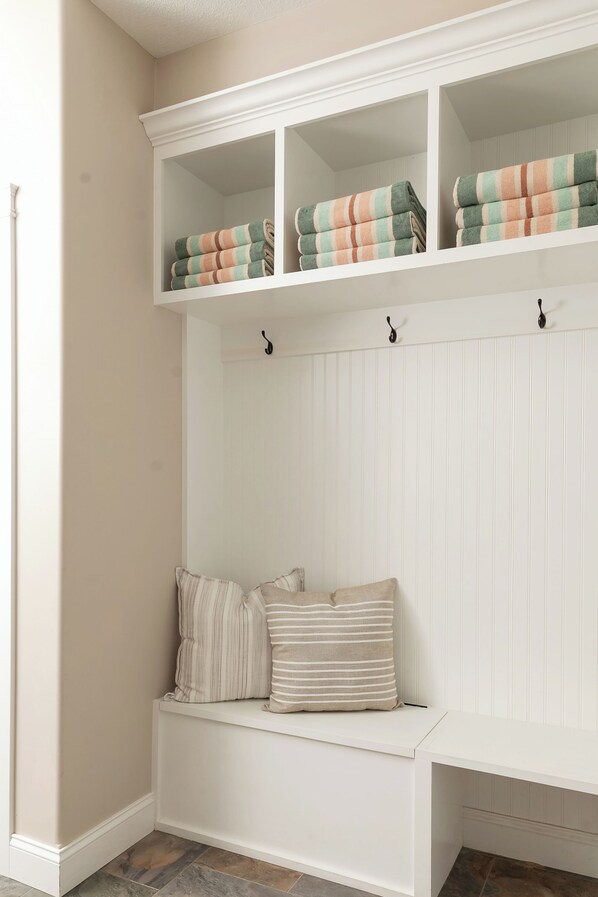 A white bench with striped cushions and a white wall with vertical paneling. - Spectacular Lakefront Retreat on Lake Michigan in Suttons Bay (Suttons Bay)