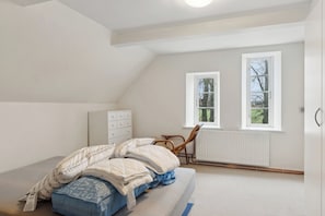 A bedroom with a bed, a dresser, a chair, and two windows. - Countryside property with great fishing options (Holbæk)