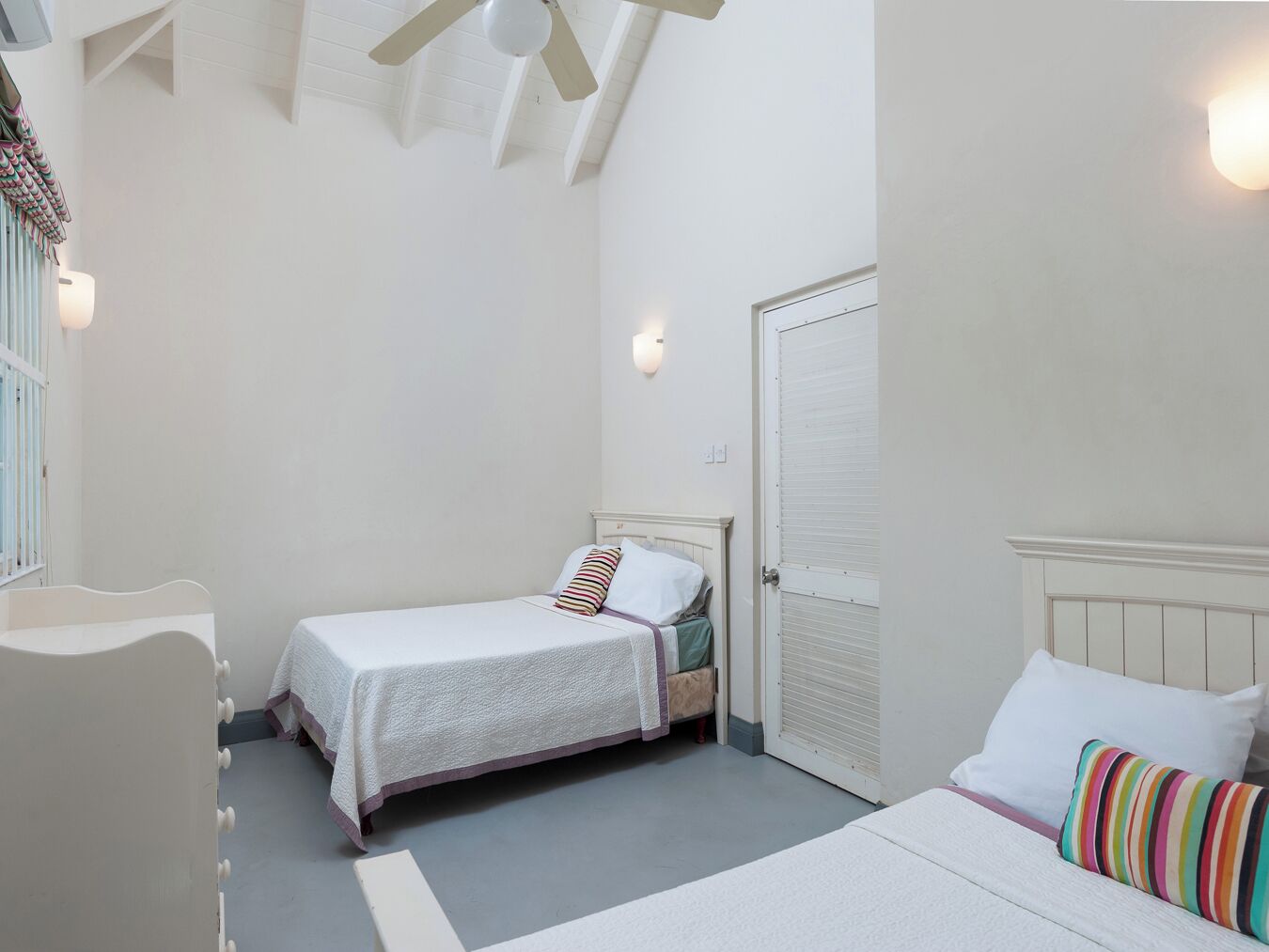 A small, well-lit bedroom with a single bed, a chair, and a door.