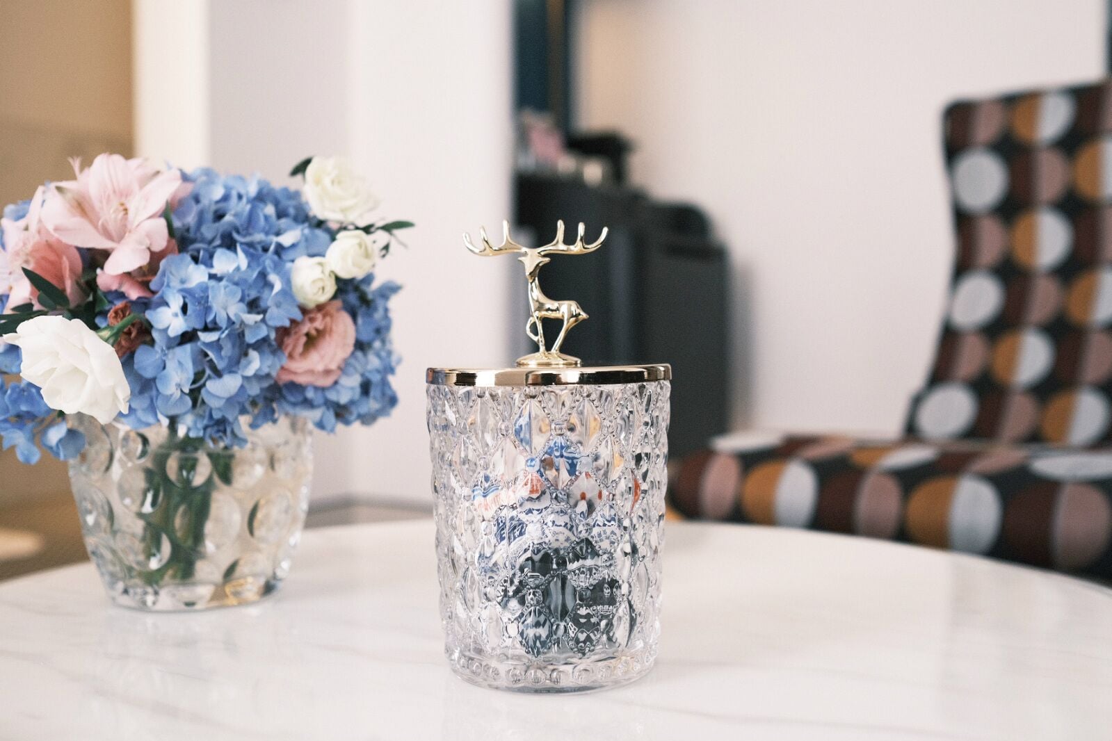 A table with a crystal vase and a crystal candle holder with a deer figurine.