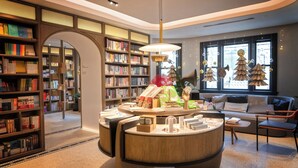 Une bibliothèque moderne avec des étagères, un espace de lecture doté d’un canapé et de fauteuils, et des sapins de Noël décoratifs.