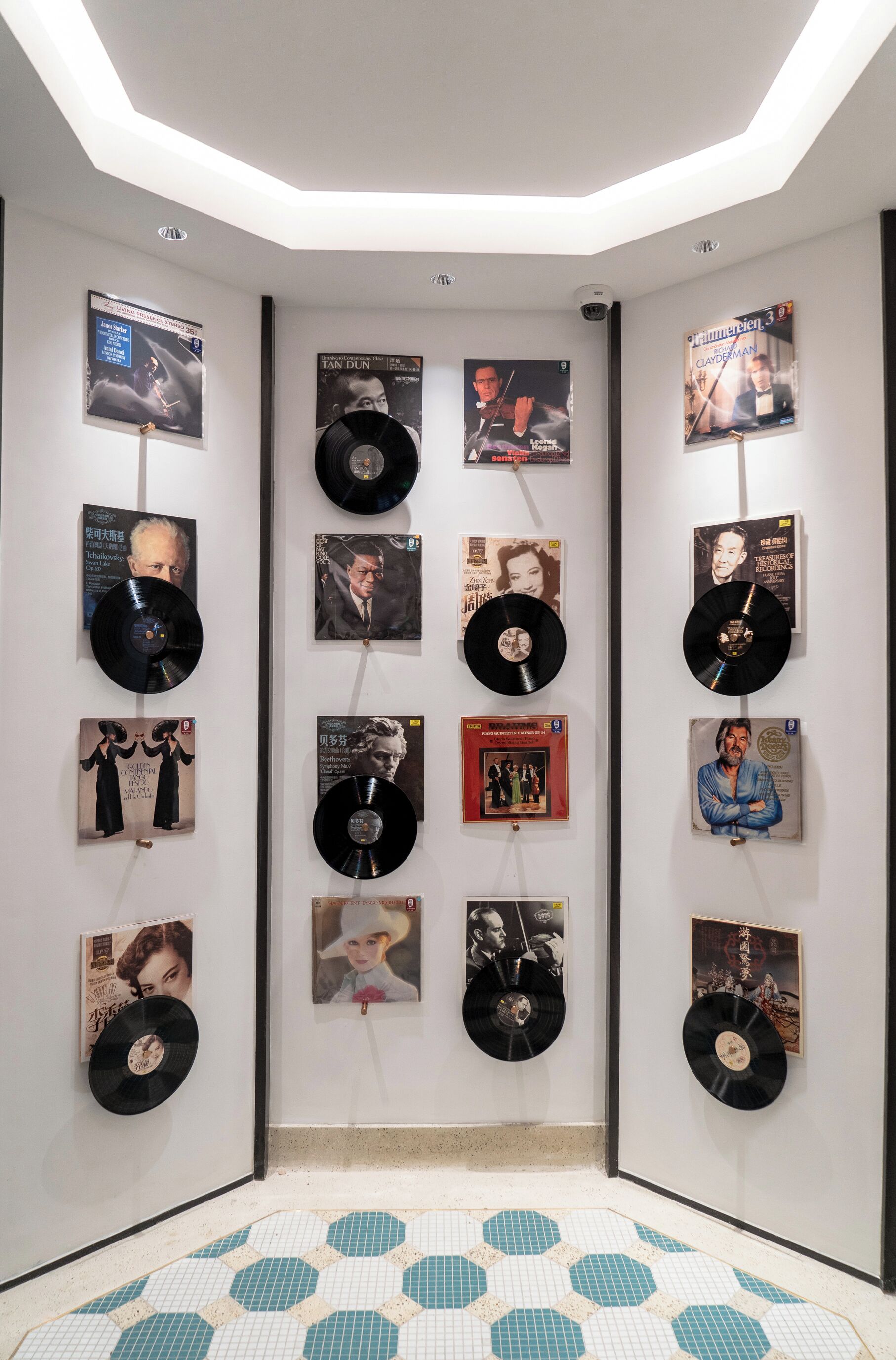 A room with a wall displaying various album covers and vinyl records.