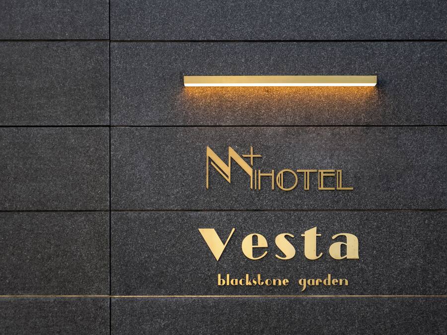 A hotel sign with the name "Vesta" and the tagline "blackstone garden" on a dark stone wall.