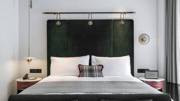 Una habitación de hotel moderna con una cama grande, una mesita de noche con lámpara, radio y toma de corriente.