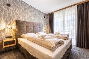 A hotel room with a large bed, a headboard, a bedside table, and a window with curtains. - Apartment in Fugen Near Thermal Spring (Fuegen)
