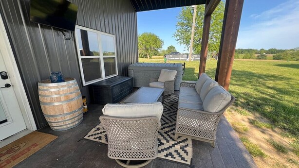 An outdoor patio with wicker furniture, a television, and a barrel. - Relax Enjoy Country Living-Hot Tub & Seasonal Pool (New Franklin)