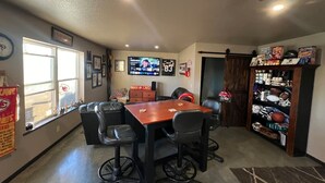 A room with a wooden table and four chairs, a television mounted on the wall, and a bookshelf filled with sports memorabilia. - Relax Enjoy Country Living-Hot Tub & Seasonal Pool (New Franklin)