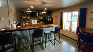 Een keuken met een bar, krukken en uitzicht op buiten.