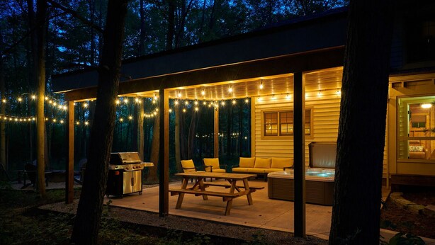 An outdoor patio area with string lights, a grill, and seating. - Dollybrook 1: Dreamy Den | Hot Tub & Pool (Fennville)