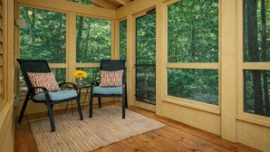 A room with large windows, two chairs, a small table, and a rug. - Dollybrook 1: Dreamy Den | Hot Tub & Pool (Fennville)