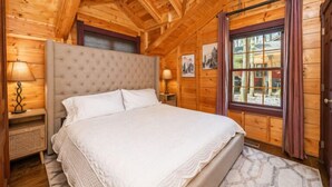A wooden cabin bedroom with a bed, a window, and a ceiling fan.