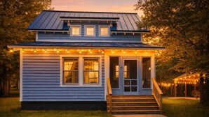 Una casa a due piani con un portico, una piccola scalinata e una zona coperta decorata con luci decorative.