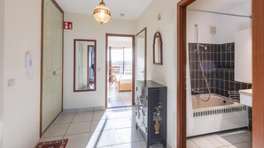 A hotel hallway with a bathroom featuring a bathtub and a shower.