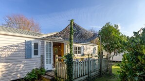 A single-story house with a covered porch, a wooden fence, and a small garden area. - La Spatule by Interhome (Carnac)