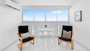 A modern room with a large window, two chairs, a small table, and a potted plant. - Chic Studio in Condado | Beach at Your Doorstep (San Juan)